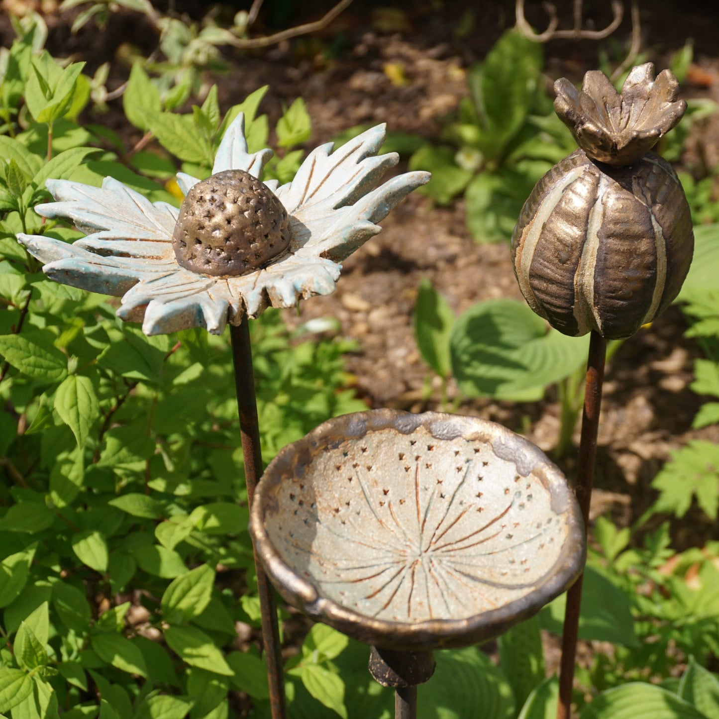 Seed heads garden art created by beginner during one day workshop. Sea holly, poppy seed head and cow parsley bird drinker.