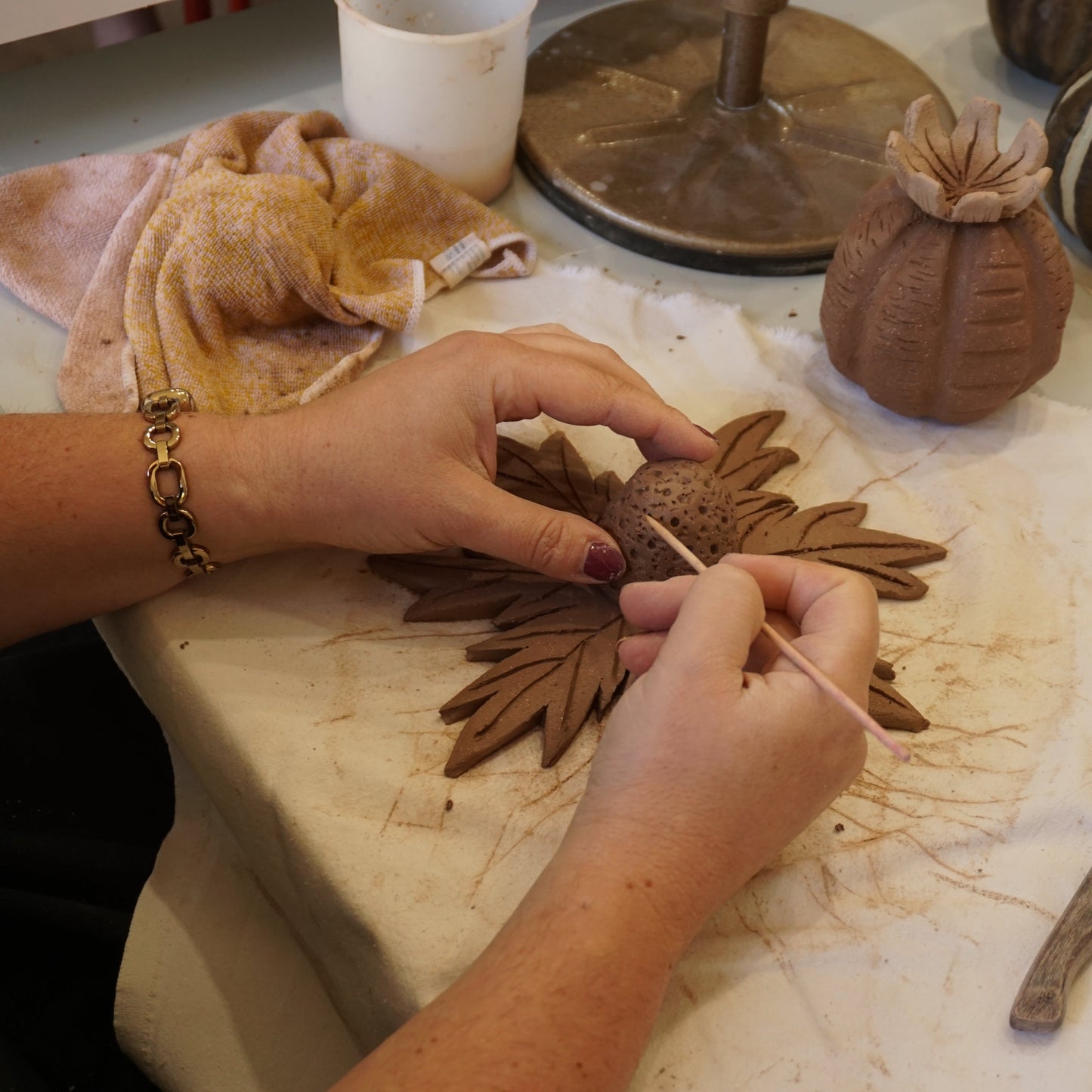 Student adding texture to sea holly garden art during workshop