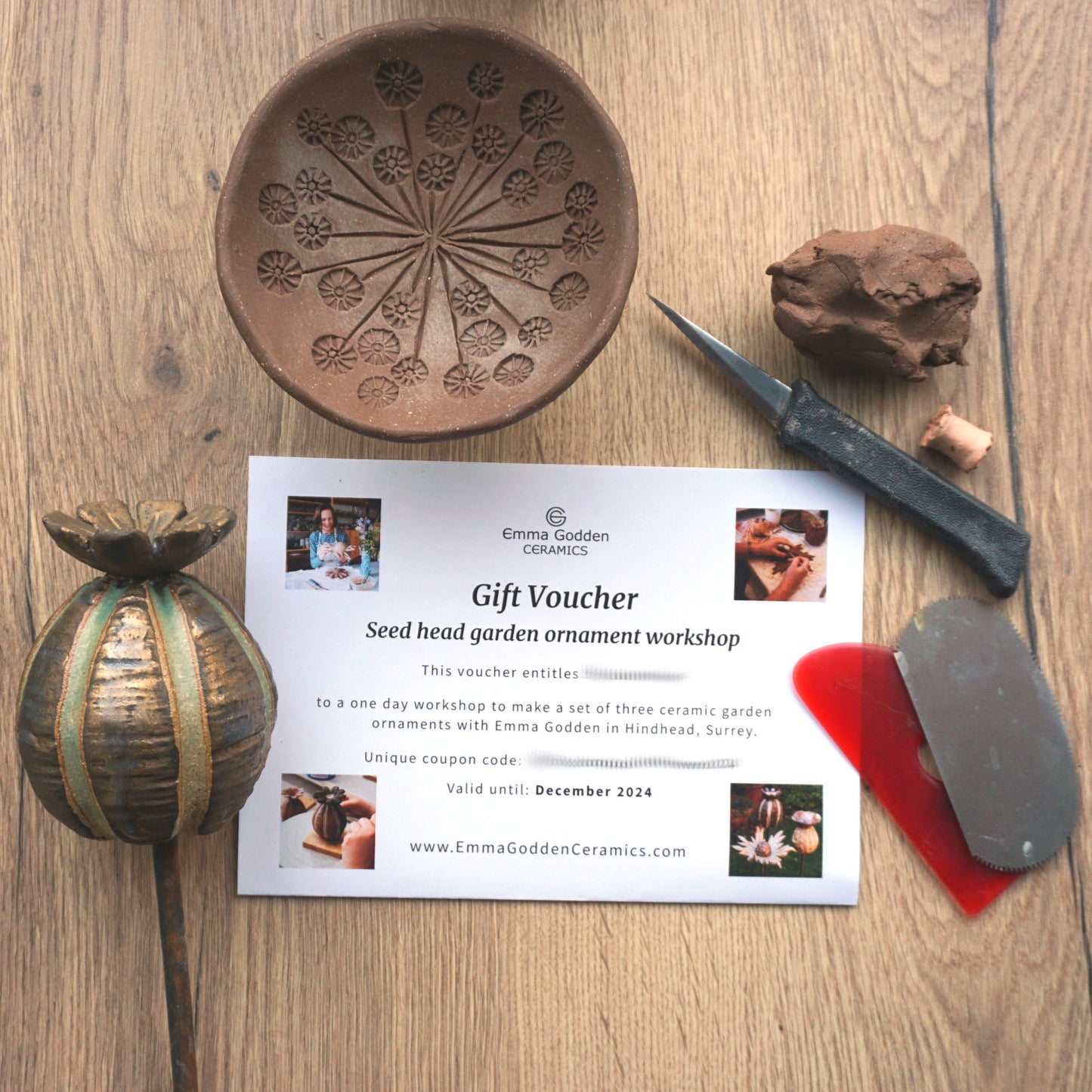 gift voucher with finished example poppy seed head ceramic garden ornament, bird drinker in progress and pottery tools and lump of clay.