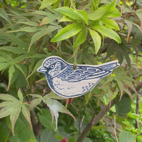 Ceramic sparrow hanging decorations hanging outside in tree