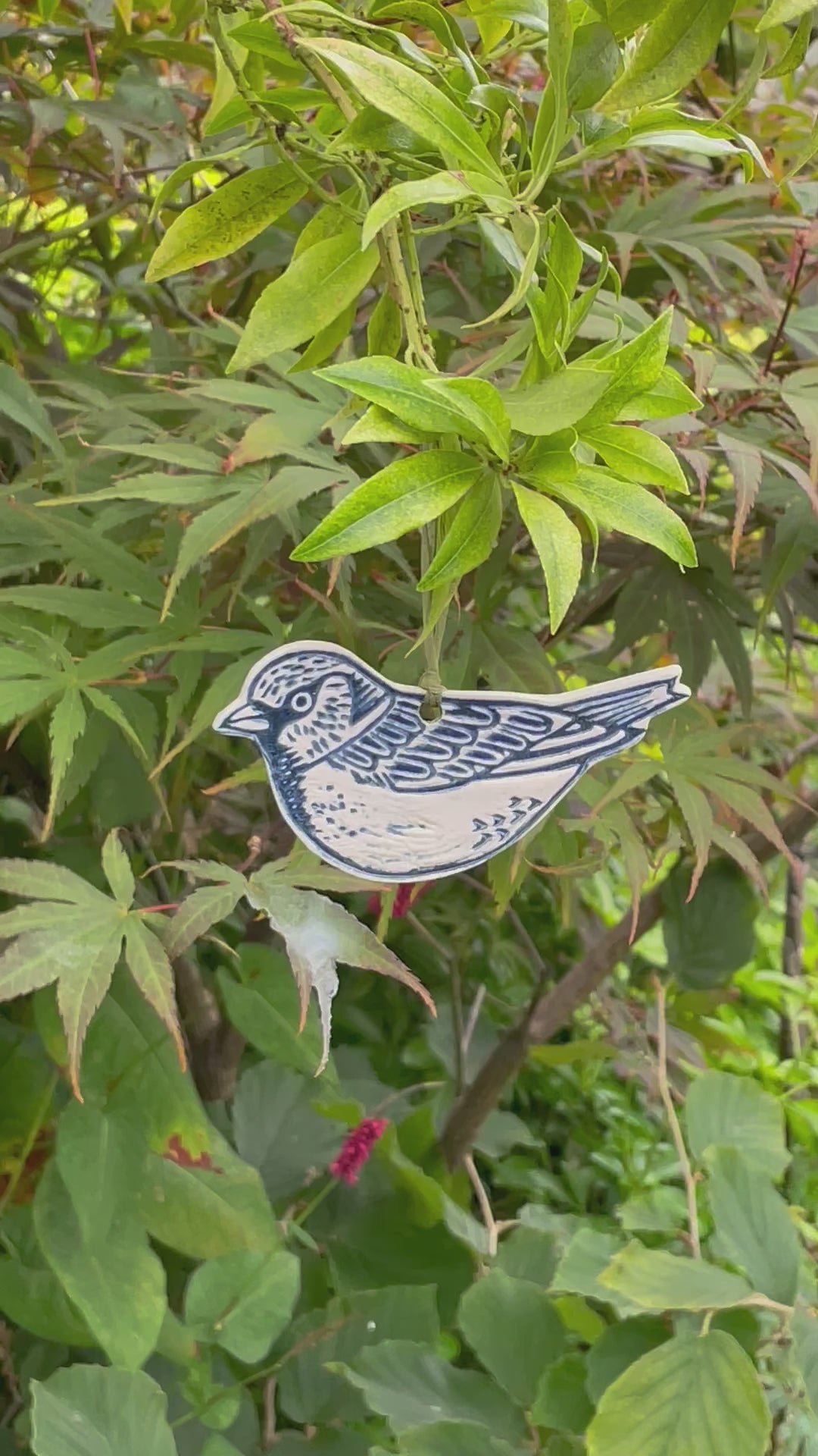 Ceramic sparrow hanging decorations hanging outside in tree