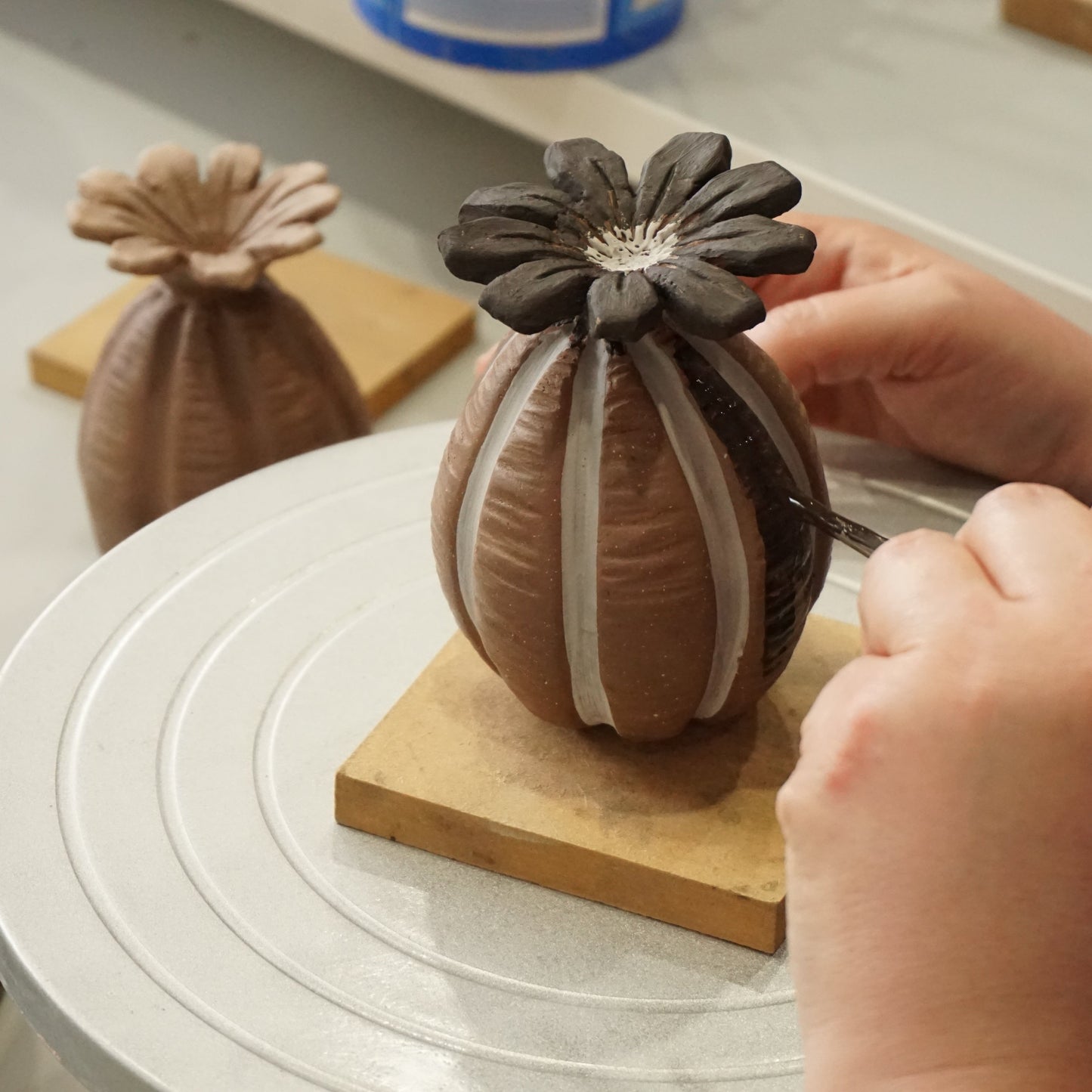 Student painting glaze onto poppy seed head garden ornament during a one day workshop